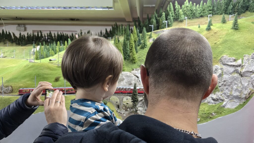 Besucher des Fahrtags (Vater und Sohn) betrachten den vorbeifahrenden Bernina Express.